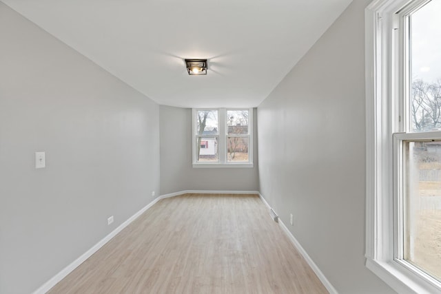 unfurnished room with light wood finished floors, baseboards, and visible vents