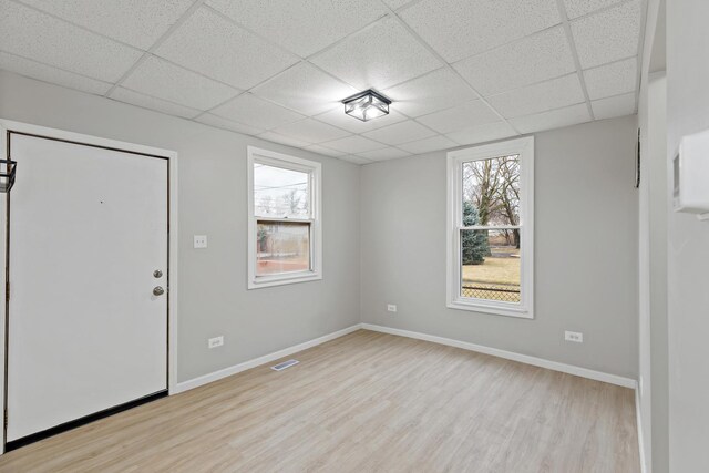 foyer entrance featuring a drop ceiling, light wood-style flooring, a wealth of natural light, and visible vents