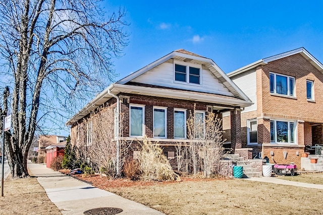 bungalow with covered porch and brick siding