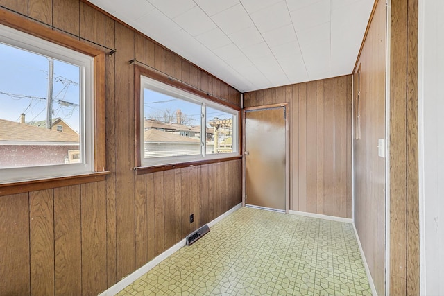 spare room featuring baseboards, wood walls, and light floors