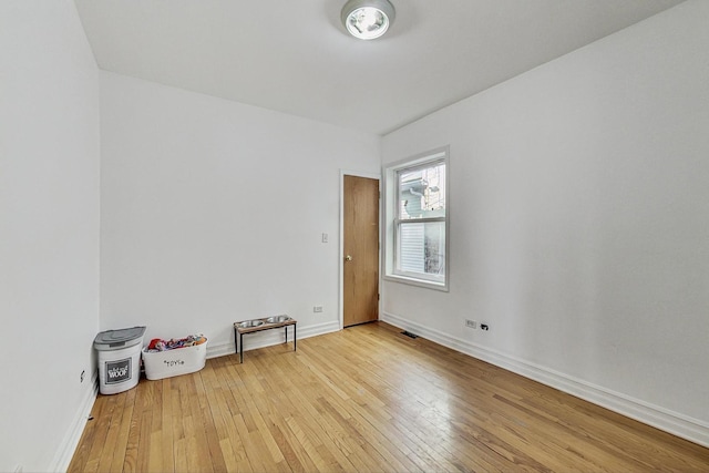 unfurnished room featuring hardwood / wood-style floors, visible vents, and baseboards