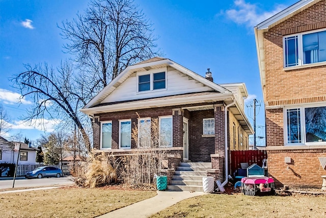 bungalow-style home with brick siding, fence, and a porch