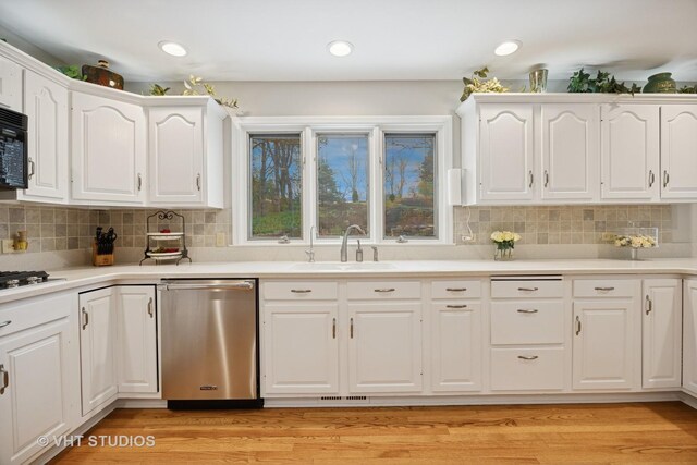kitchen with a sink, white cabinets, backsplash, and dishwasher