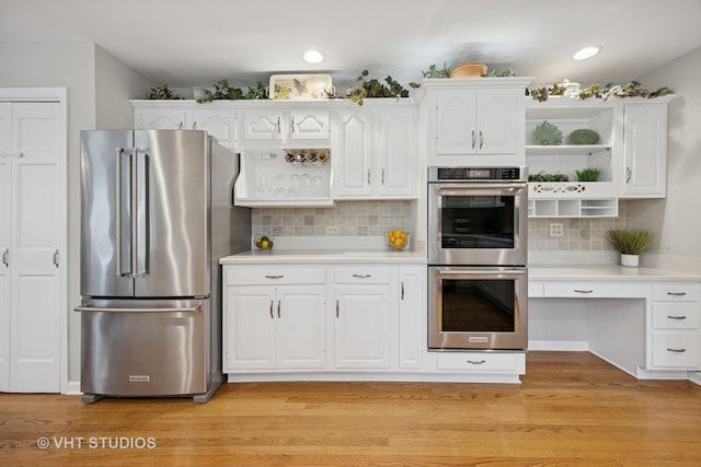 kitchen with white cabinets, open shelves, appliances with stainless steel finishes, light countertops, and decorative backsplash