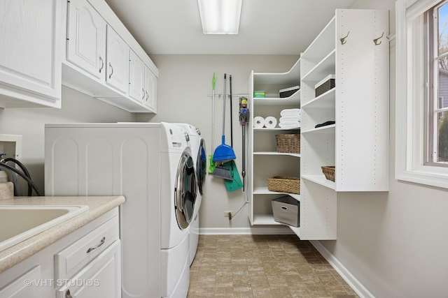 washroom with cabinet space, baseboards, stone finish flooring, and washing machine and dryer