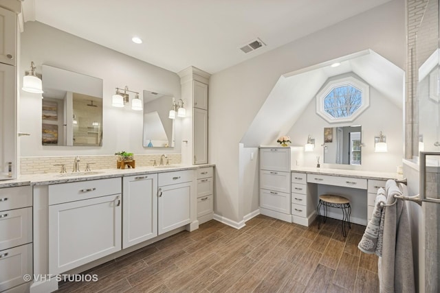 full bathroom featuring double vanity, visible vents, a sink, and lofted ceiling