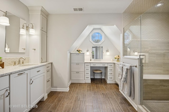 full bath with visible vents, wood finished floors, and tiled shower