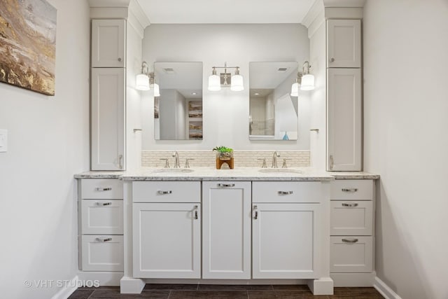 bathroom with baseboards, a sink, and double vanity