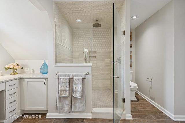 bathroom with wood finished floors, toilet, baseboards, tiled shower, and recessed lighting