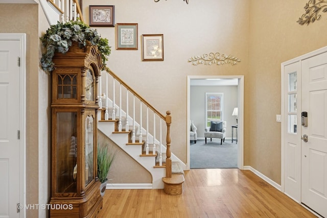 foyer with baseboards, a high ceiling, wood finished floors, and stairway