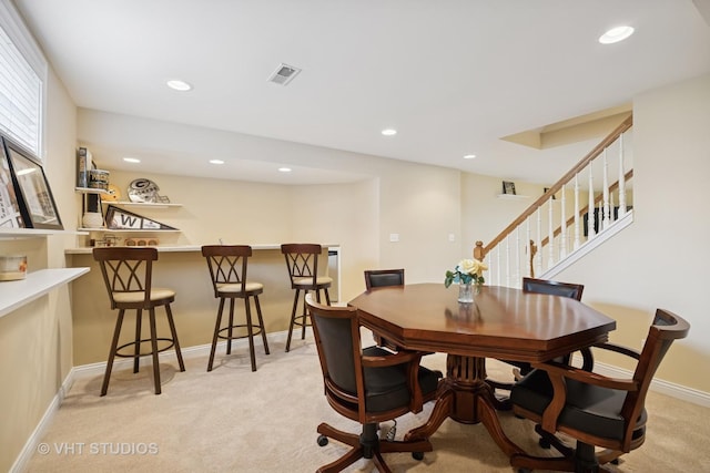 dining area featuring light colored carpet, a dry bar, recessed lighting, and stairway