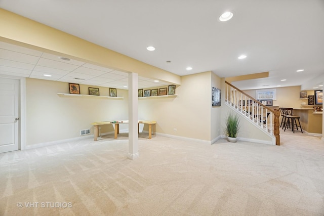 finished below grade area with visible vents, stairway, carpet floors, baseboards, and bar area