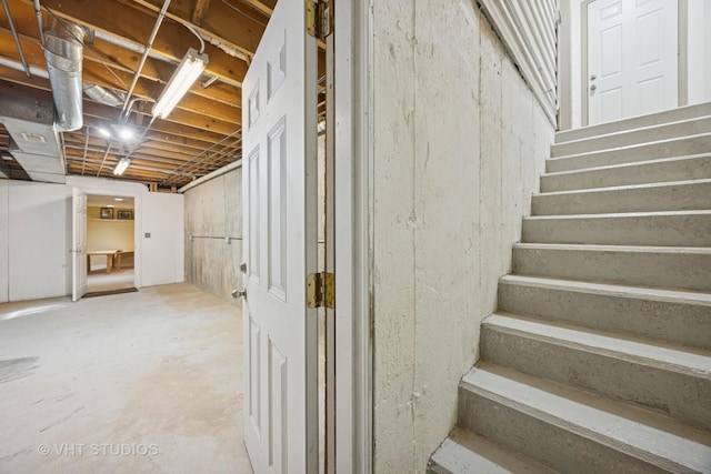 staircase with unfinished concrete floors