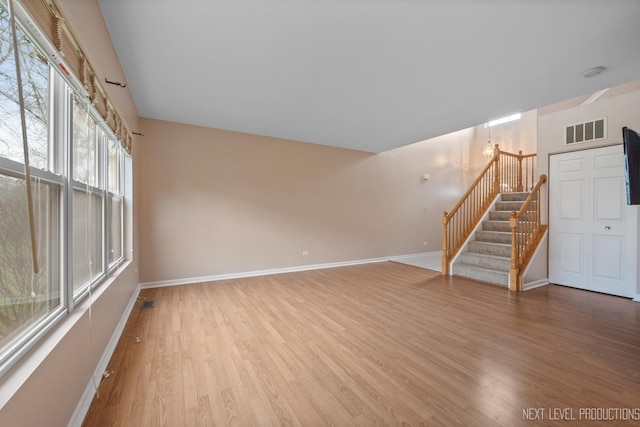 unfurnished living room featuring visible vents, stairway, wood finished floors, and baseboards
