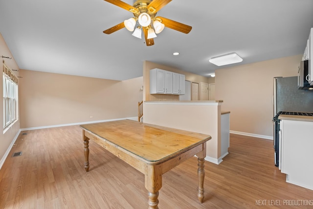 interior space featuring baseboards, light wood-type flooring, visible vents, and a ceiling fan