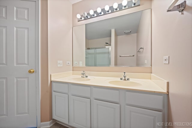 full bathroom featuring double vanity, visible vents, a shower with door, and a sink