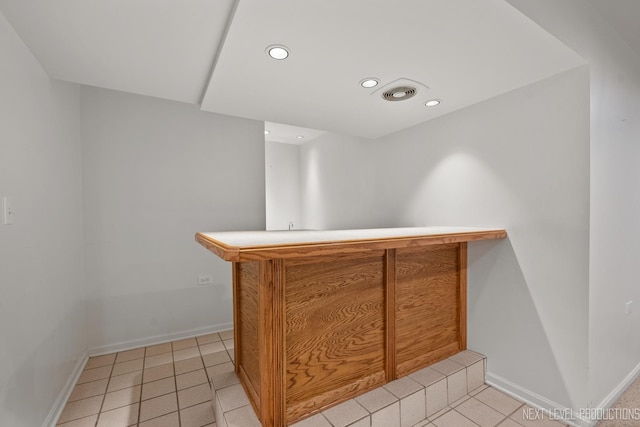 bar featuring light tile patterned floors, recessed lighting, bar area, and baseboards