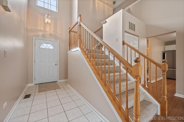 foyer entrance with baseboards, visible vents, and a towering ceiling