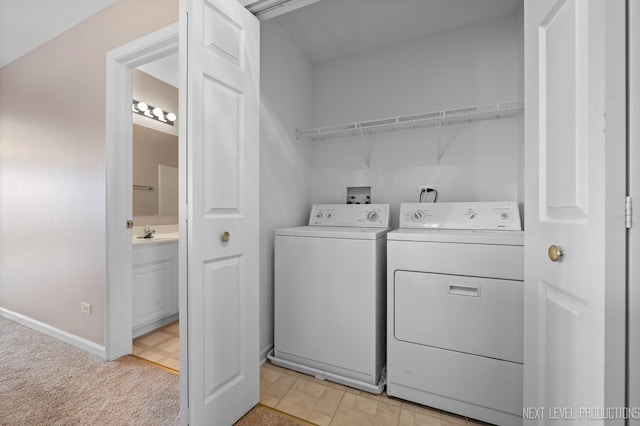 laundry area with a sink, light colored carpet, baseboards, washer and dryer, and laundry area