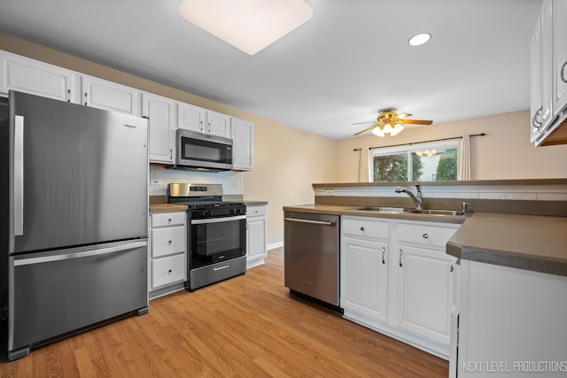 kitchen with appliances with stainless steel finishes, ceiling fan, backsplash, a sink, and white cabinetry