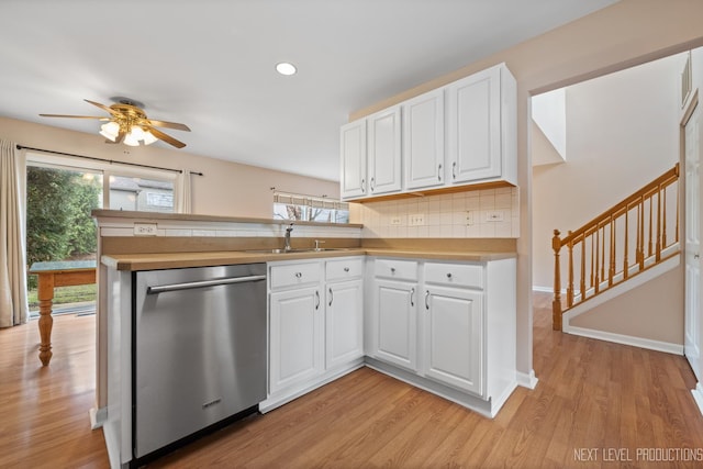 kitchen with stainless steel dishwasher, ceiling fan, light wood finished floors, a peninsula, and backsplash