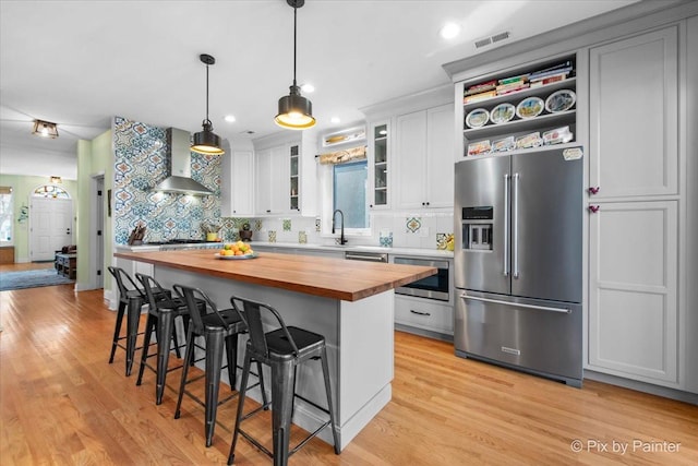 623 Oakton St, Evanston, IL 60202 - kitchen with a sink, tasteful backsplash, butcher block countertops, appliances with stainless steel finishes, and wall chimney range hood