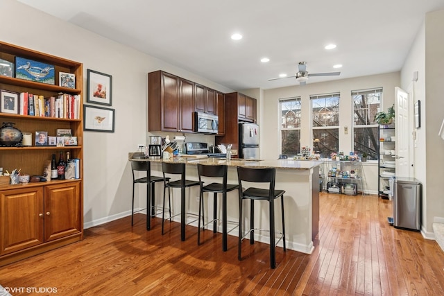 507 Grove Ln Unit H, Forest Park, IL 60130 - kitchen featuring a peninsula, fridge, light stone countertops, stainless steel microwave, and light wood-style flooring
