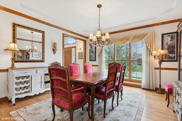 dining room featuring a notable chandelier, a raised ceiling, and light wood-type flooring