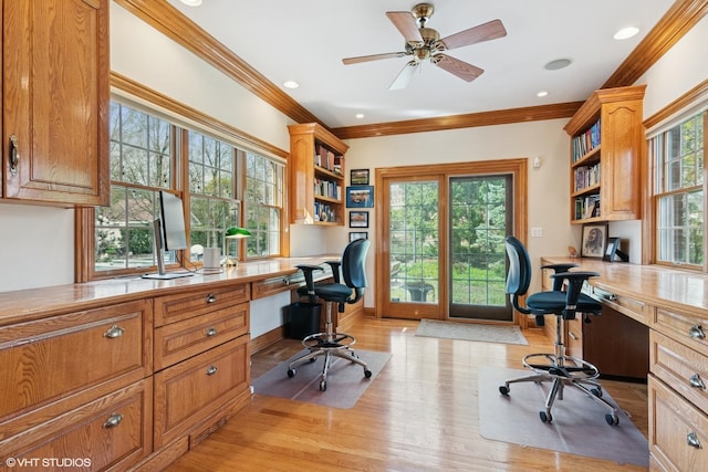 home office with light wood-style flooring, ornamental molding, and built in desk