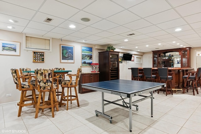 game room featuring a drop ceiling, light tile patterned flooring, visible vents, and indoor bar