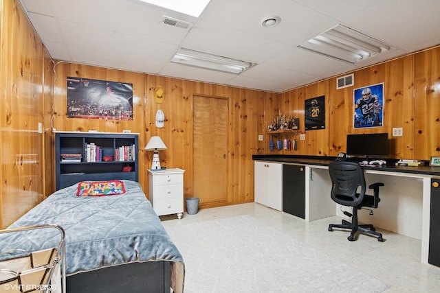 bedroom featuring wooden walls, a paneled ceiling, visible vents, and built in desk