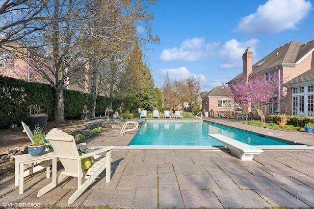 pool with a patio and a diving board