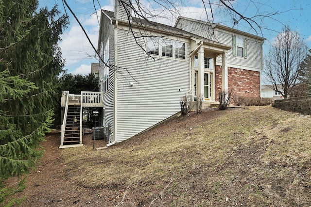 view of property exterior featuring brick siding, stairs, and a wooden deck