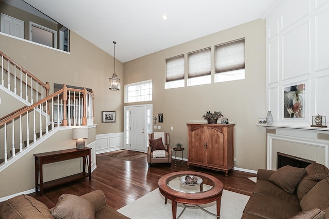 living room featuring high vaulted ceiling, wood finished floors, stairway, and a tile fireplace