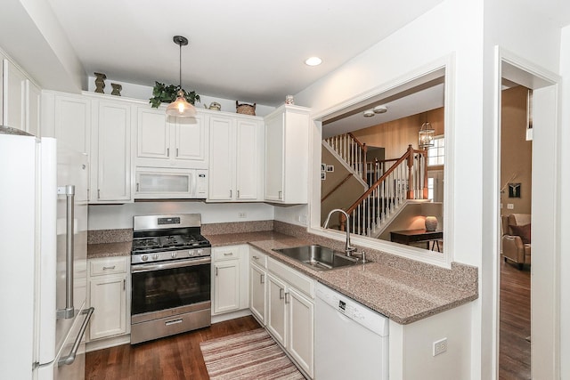 kitchen with white appliances, white cabinets, a sink, and dark wood-style floors