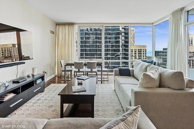 living area with a wall of windows, wood finished floors, and a view of city