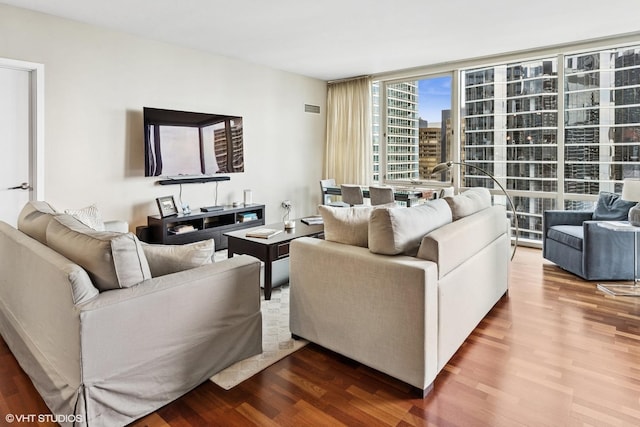 living room with wood finished floors, expansive windows, and a city view