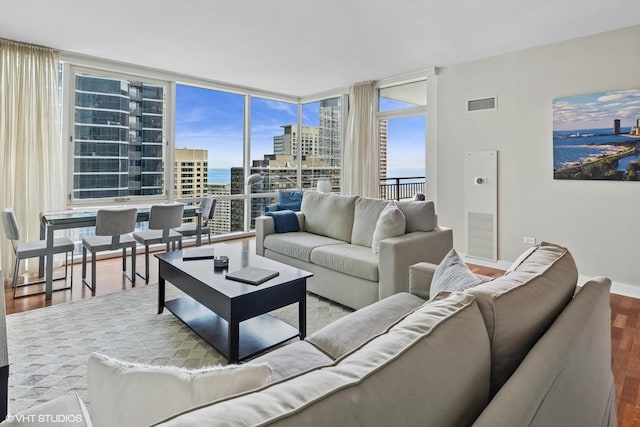 living area with wood finished floors, a city view, healthy amount of natural light, and a water view
