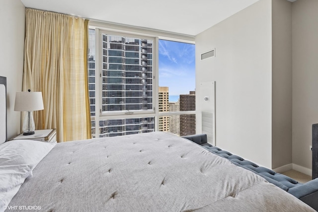 bedroom featuring floor to ceiling windows, baseboards, and a view of city