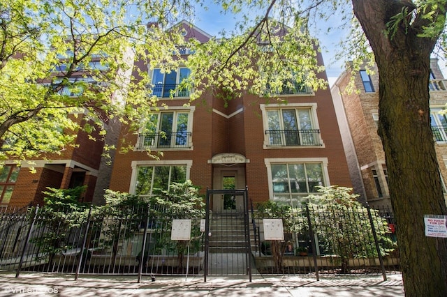 view of front of property featuring fence, brick siding, and a gate