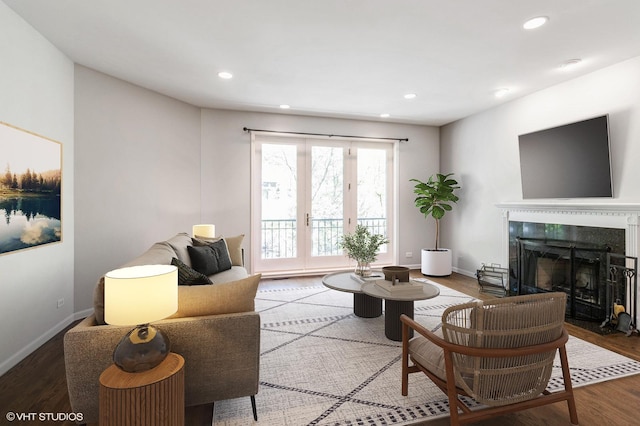 living room featuring a premium fireplace, recessed lighting, wood finished floors, and baseboards