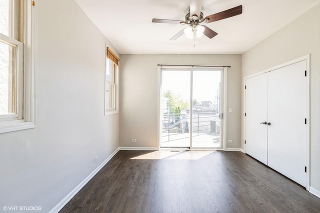 unfurnished bedroom with access to exterior, dark wood finished floors, baseboards, a closet, and a ceiling fan