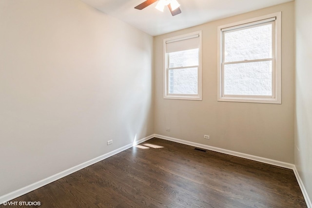 spare room with baseboards, dark wood finished floors, and a ceiling fan