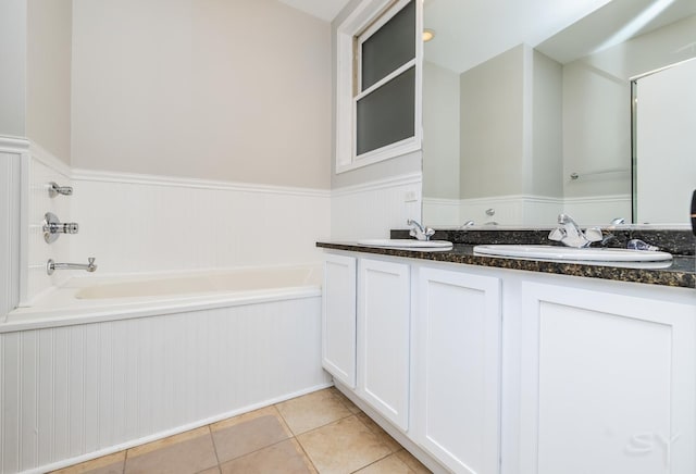 full bathroom with a wainscoted wall, a garden tub, tile patterned floors, and double vanity