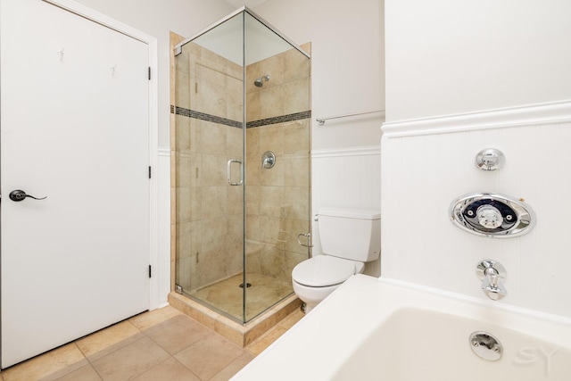 full bathroom with a stall shower, tile patterned flooring, wainscoting, and toilet