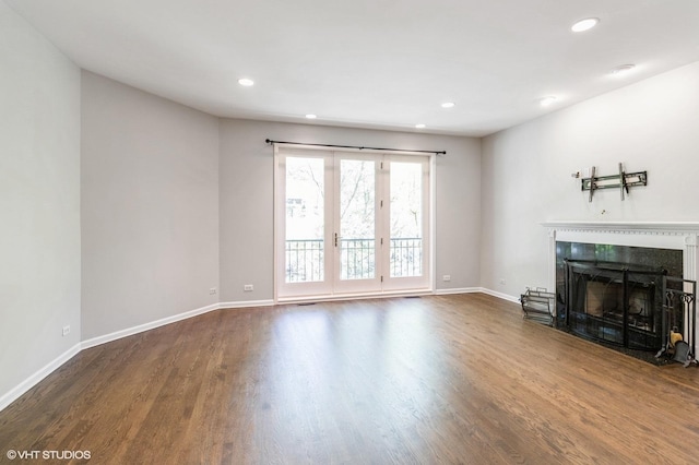 unfurnished living room with a fireplace with flush hearth, wood finished floors, recessed lighting, and baseboards