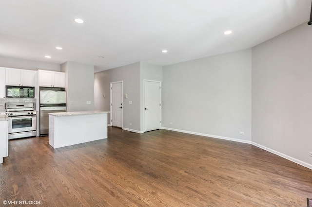 kitchen with stainless steel appliances, a center island, white cabinets, baseboards, and dark wood finished floors