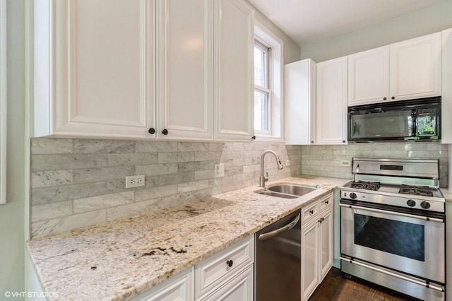 kitchen with stainless steel appliances, light stone countertops, white cabinetry, a sink, and decorative backsplash