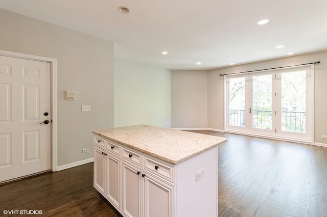 kitchen with dark wood-type flooring, baseboards, light stone countertops, recessed lighting, and a kitchen island