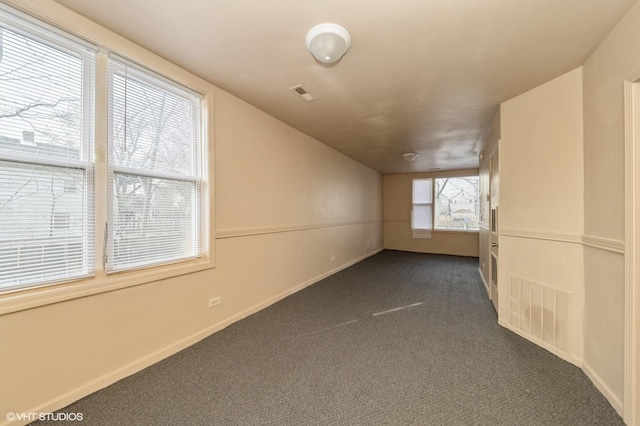 additional living space with baseboards, visible vents, and dark colored carpet